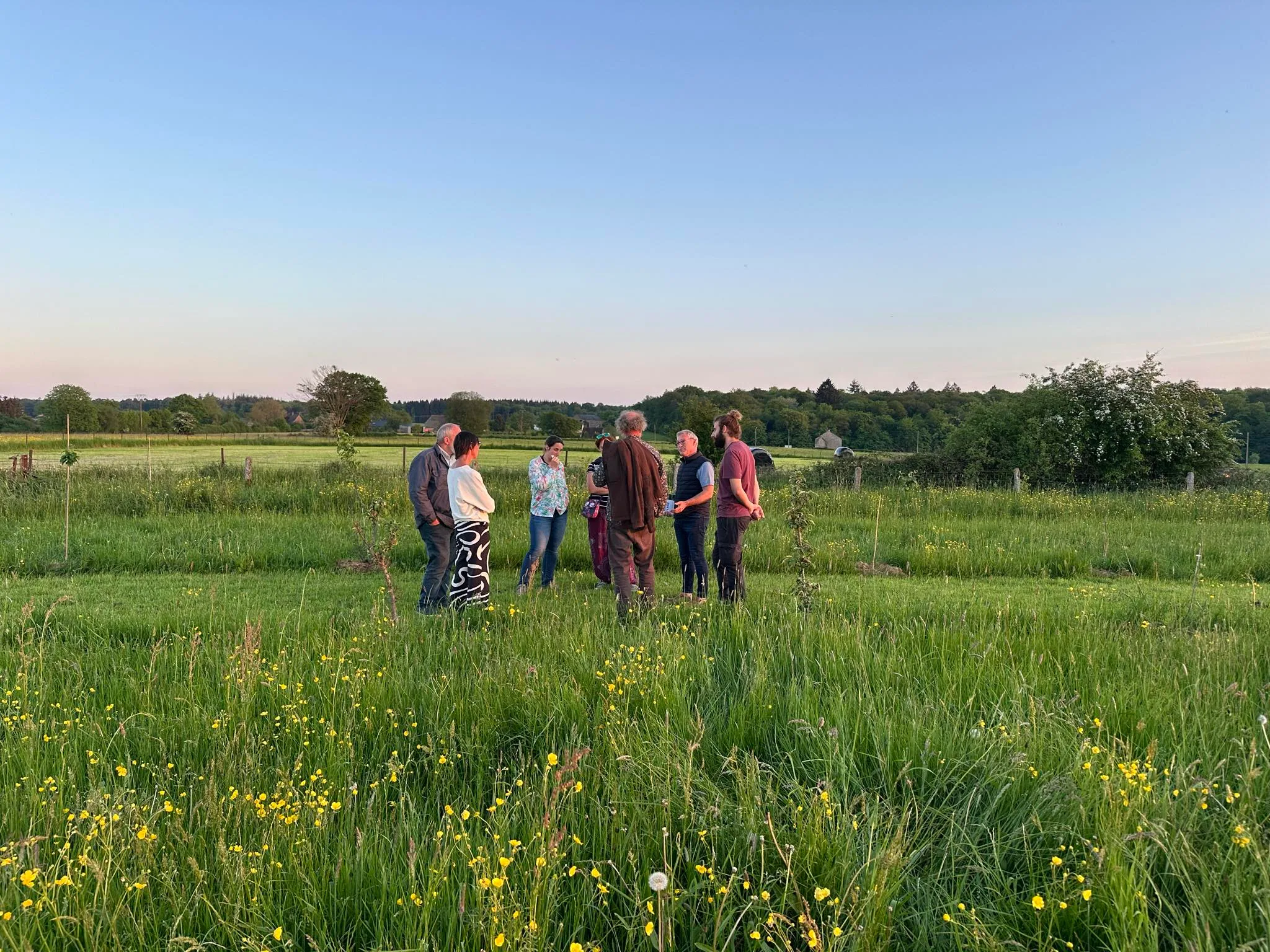 Un petit groupe échange avec Louis dans la prairie